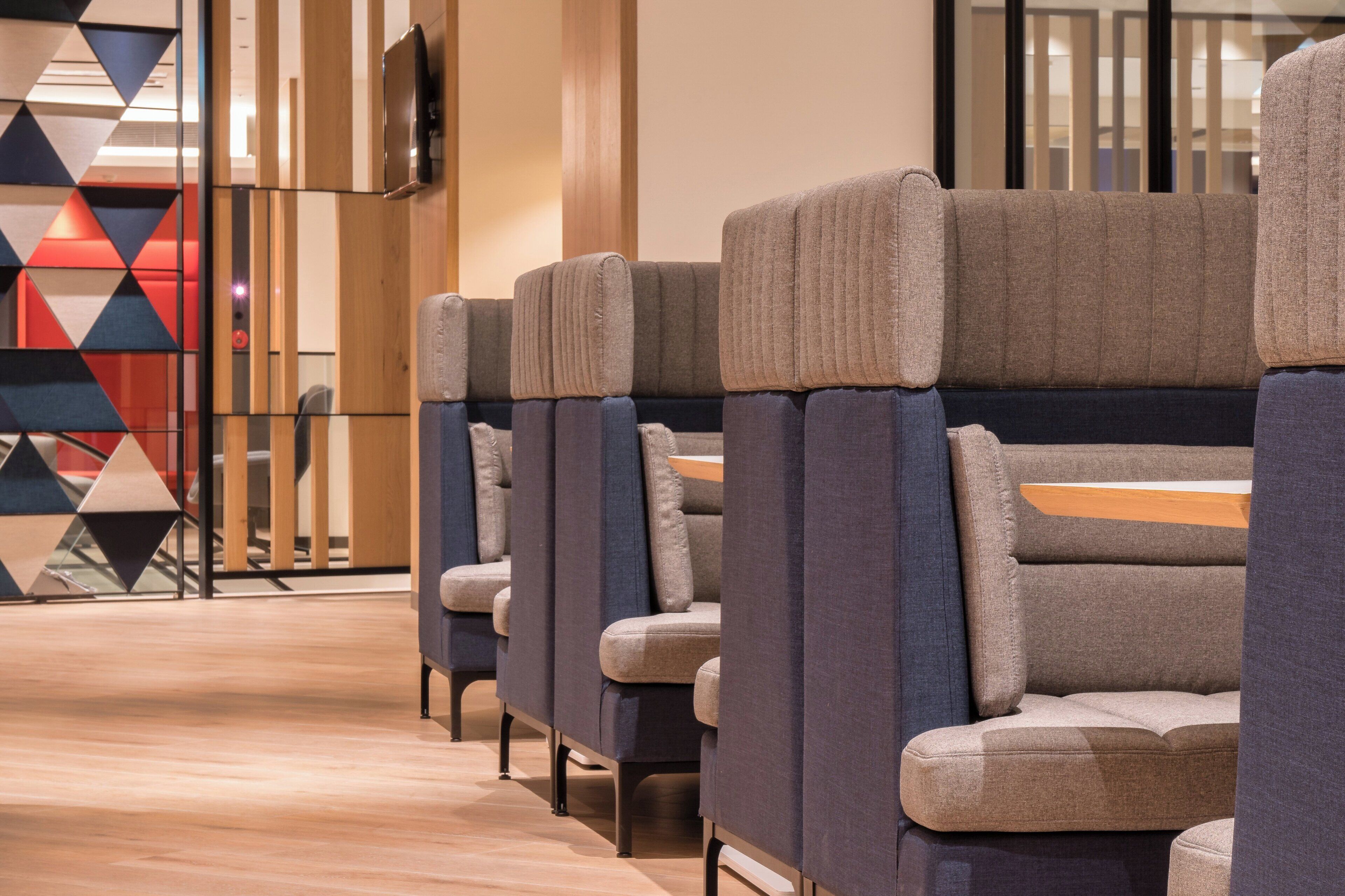 A row of modern, upholstered seating with a wooden table in a hotel lobby.