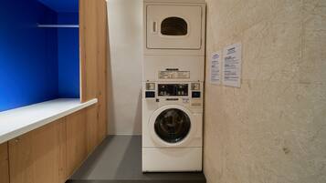 A compact, modern laundry room with a built-in washer and dryer, a wooden bench, and a blue wall.