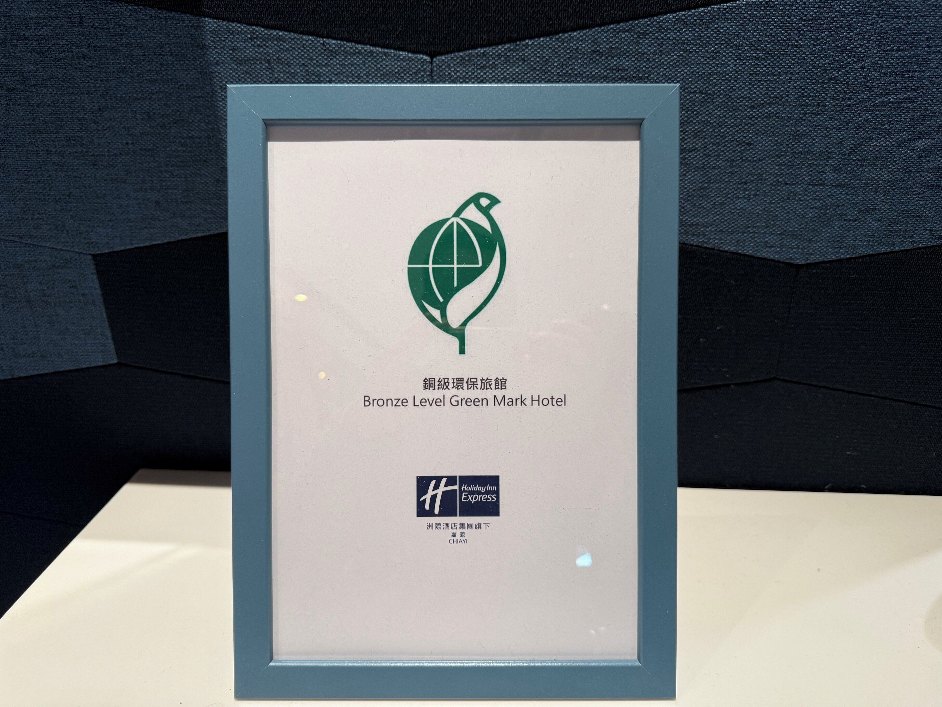 A framed certificate for the Bronze Level Green Mark Hotel, featuring a green leaf logo and hotel name in both English and Chinese.