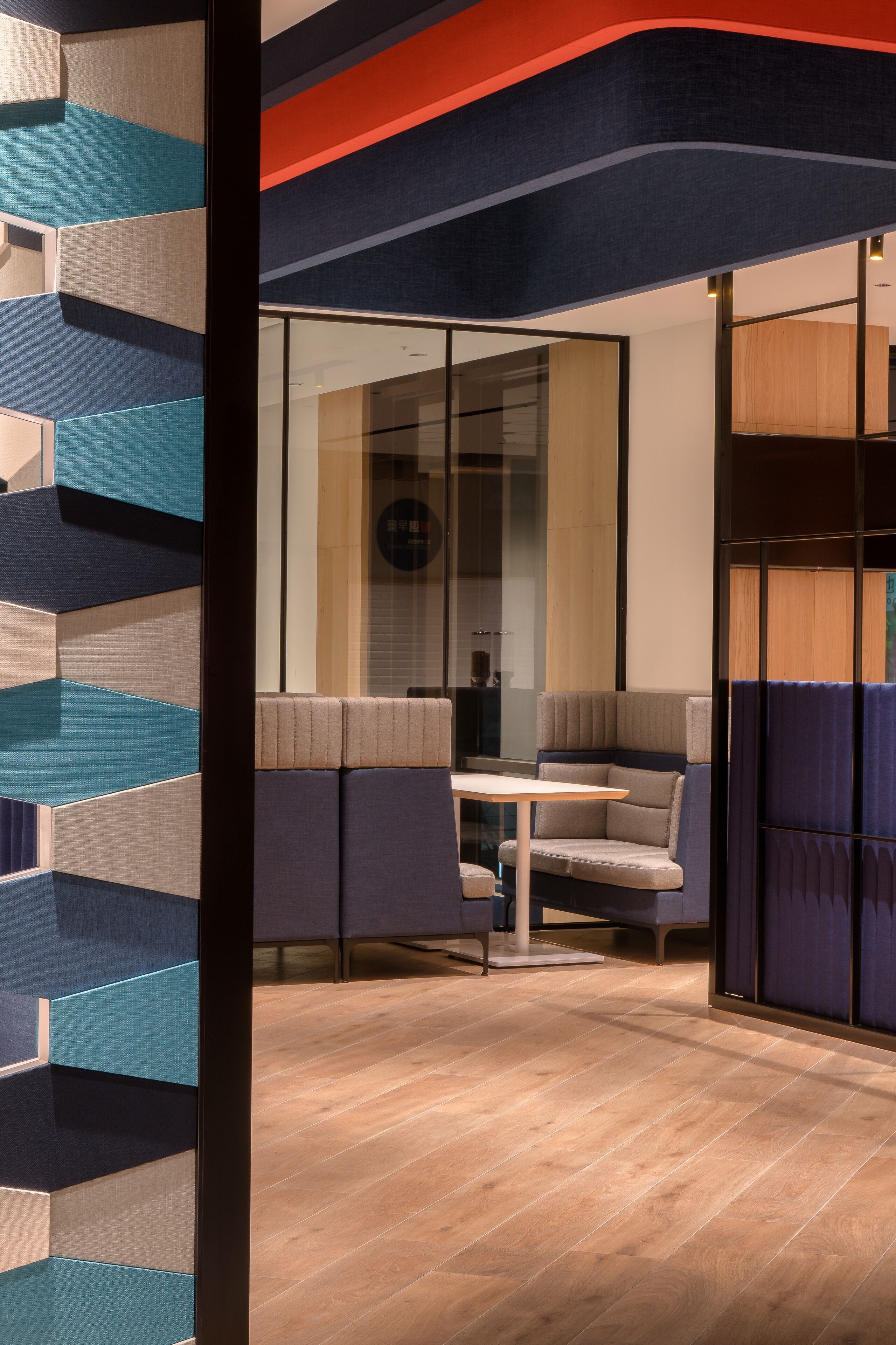 A modern interior with a geometric wall design, a seating area with a table, and a wooden floor.
