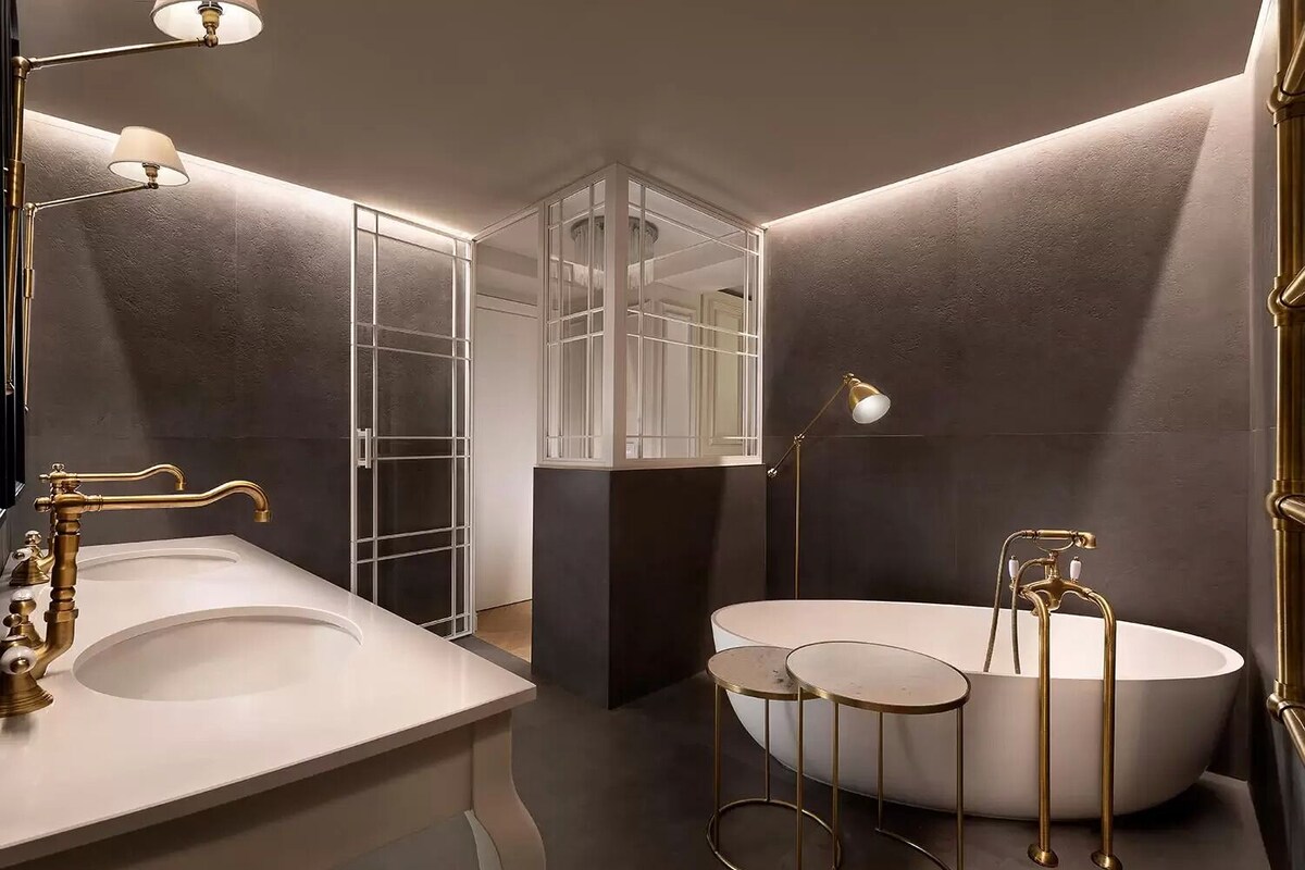 Une salle de bain moderne avec une baignoire sur pieds, deux vasques et une douche à l’italienne avec des portes en verre.