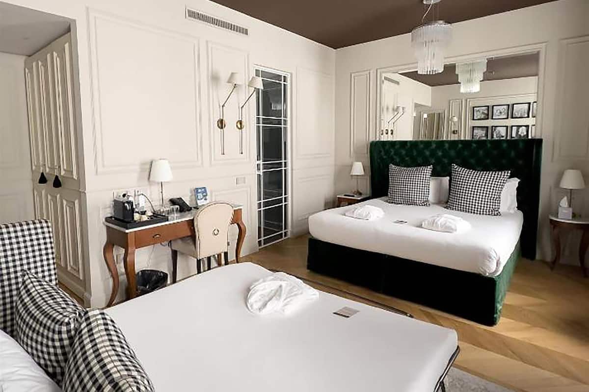 A hotel room with a large bed, a desk with a chair, a dresser, and a mirror.
