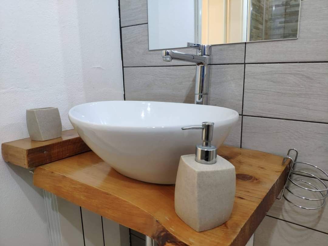Ein Badezimmer mit einem weißen Waschtisch, einem Seifenspender und einem Handtuchhalter.