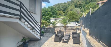 A courtyard with stone flooring, outdoor furniture, and a staircase leading to a building.