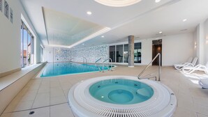 A modern indoor swimming pool with a hot tub, clear glass walls, and a tiled floor. - Apartamenty Sun & Snow Waterlane Island (Gdansk)