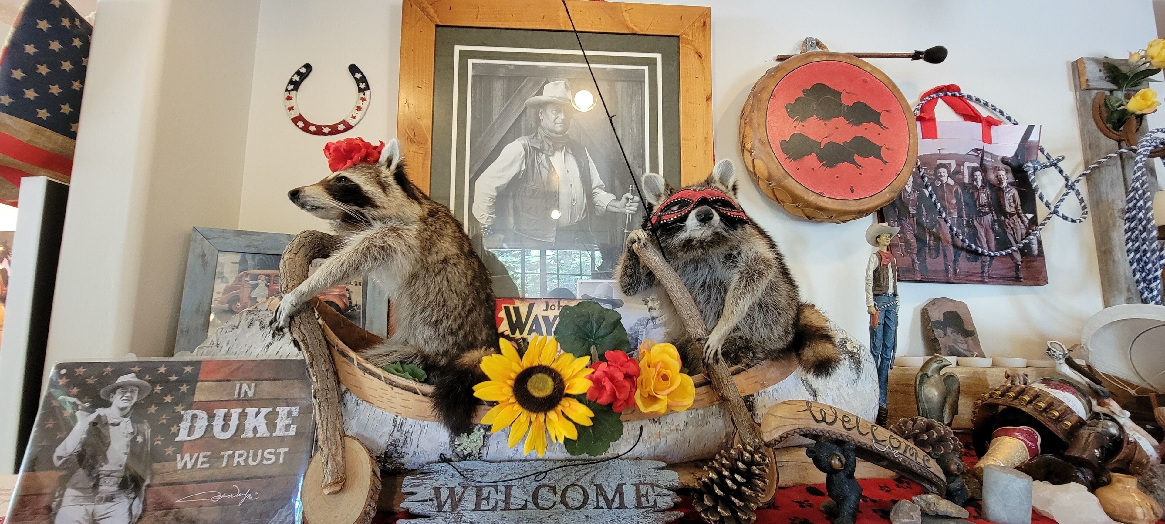 Une pièce décorée dans un style rustique, avec notamment une figurine de raton laveur, un tournesol et une pancarte « Bienvenue ».
