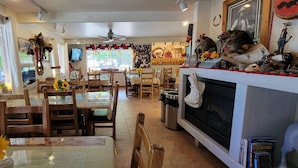 A cozy dining area with wooden chairs and tables, a fireplace, and various decorations including a TV and wall art. - Hot Springs Inn (Ouray)