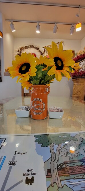 A table with a vase of sunflowers, a mug with a message, and a map of the Gold Mine Tour.