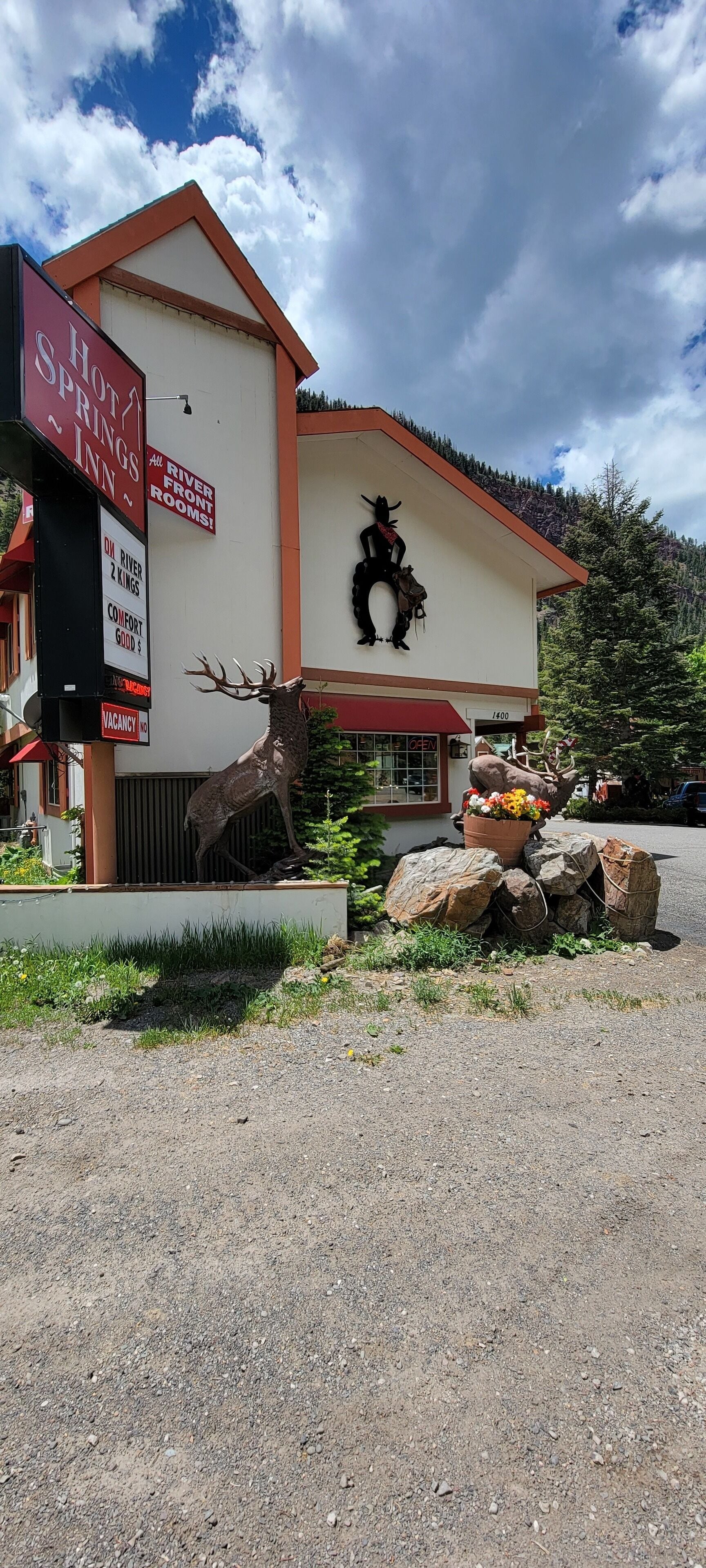 A building with a sign for "HOT SPRINGS INN" and a deer sculpture.