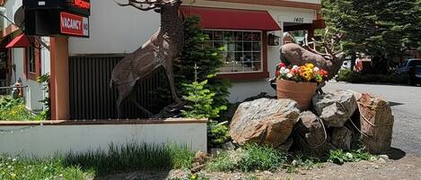 A building with a sign for "HOT SPRINGS INN" and a deer sculpture.