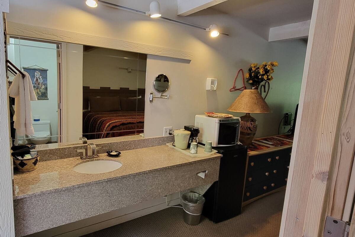 A bathroom with a sink, mirror, towel rack, and a small trash bin.