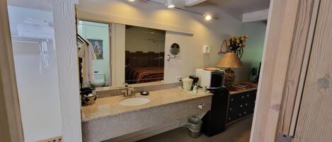 A bathroom with a sink, mirror, towel rack, and a small trash bin.
