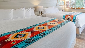A hotel room with two beds, white bedding, a colorful blanket, and wall-mounted lights. - Hot Springs Inn (Ouray)