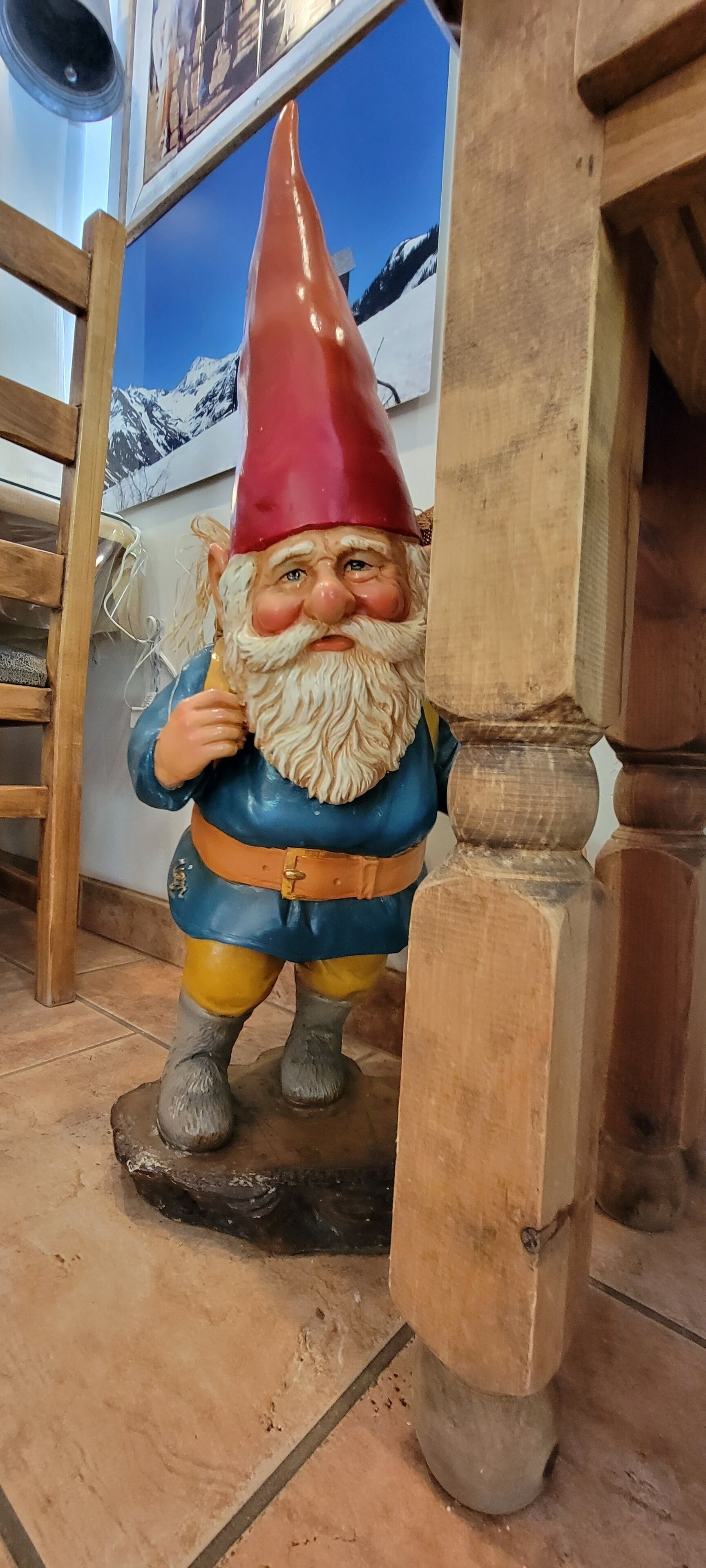 Une table en bois sur laquelle est posée une figurine de gnome, le tout sur un sol carrelé.