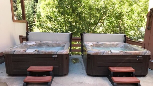 Two hot tubs with wooden steps and a view of trees. - Hot Springs Inn (Ouray)