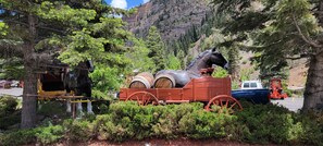 A horse-drawn carriage with barrels in a forested area.
