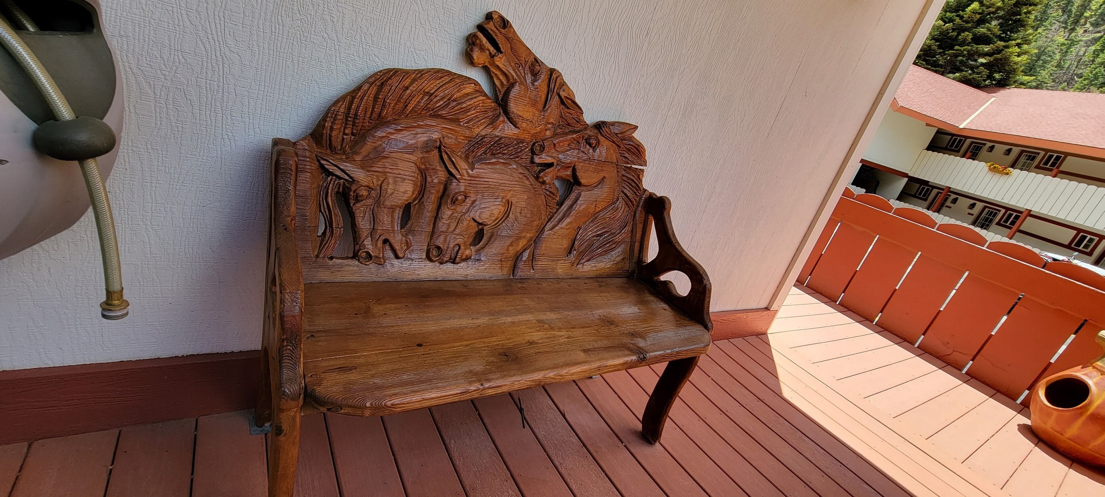 A wooden bench with horse carvings on a balcony.