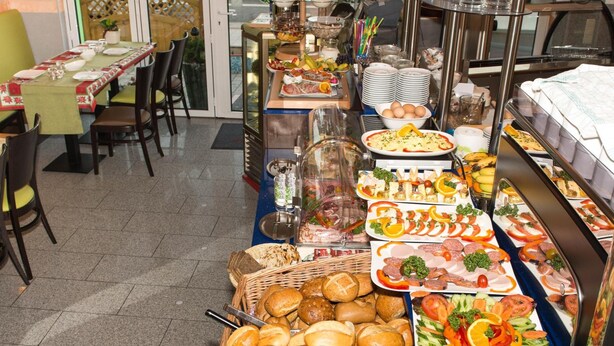 A buffet with various food items and a seating area with tables and chairs. - Hotel Sonne am Meer (Norden)