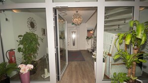 A hotel lobby with a wooden floor, a chandelier, and potted plants. - Hotel Sonne am Meer (Norden)