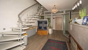 A modern hotel lobby with a staircase, a reception desk, a check-in counter, and a reception area. - Hotel Sonne am Meer (Norden)
