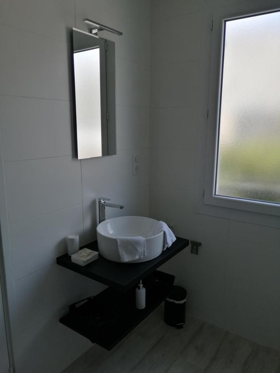 A bathroom with a white sink, a mirror, and a window.