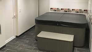 A modern bathroom with a large bathtub, a bench, and a tiled shower area.