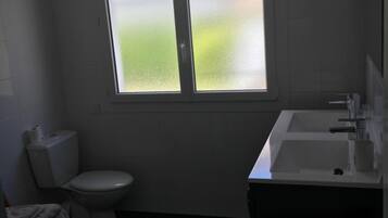 A small, modern bathroom with a toilet, sink, and window.