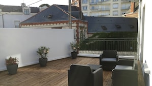A wooden deck with wicker furniture and potted plants.