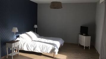 Quarto com cama, duas mesas de cabeceira com abajures, cômoda e televisão.