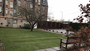Ein gepflegter Rasen mit Steinborder, einer Bank und einem Gebäude im Hintergrund.