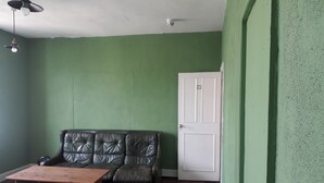 A room with a green wall, a white door, a leather sofa, a wooden table, and a ceiling fan. - St Nicholas Street Apartment (Bristol)