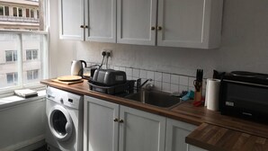 A kitchen with white cabinets, a washing machine, a toaster, and a microwave. - St Nicholas Street Apartment (Bristol)