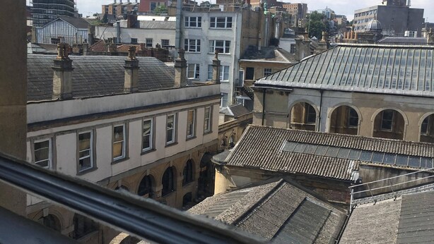A view of a cityscape with historic buildings, including a building with a tiled roof and arched windows. - St Nicholas Street Apartment (Bristol)