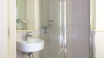 Une salle de bain avec une douche à parois de verre, un lavabo blanc et un miroir au-dessus du lavabo.