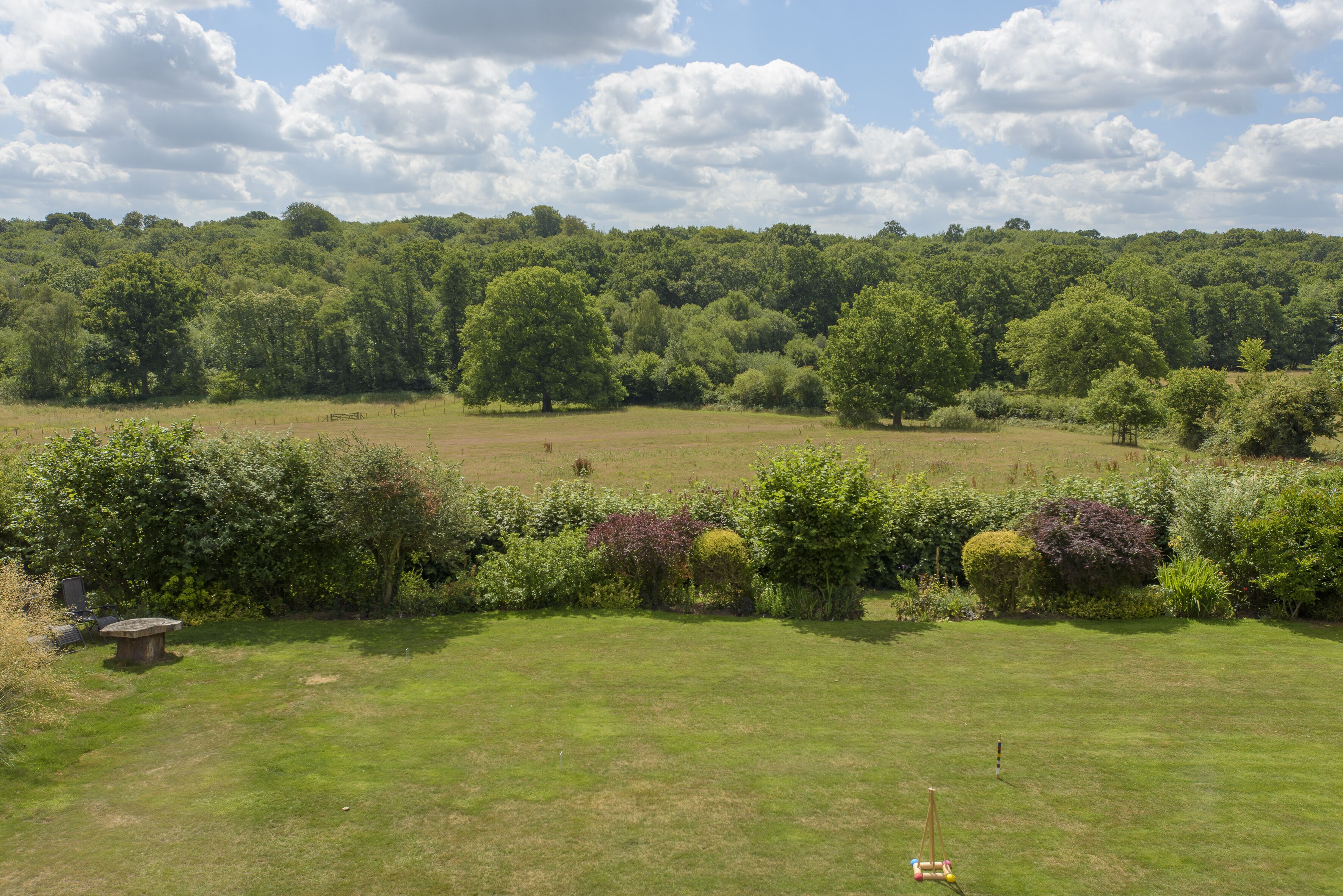 A grassy field with a stone bench and a small flagpole.