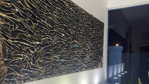 Una moderna zona de recepción con pared texturizada, iluminación empotrada y un espacio de descanso.