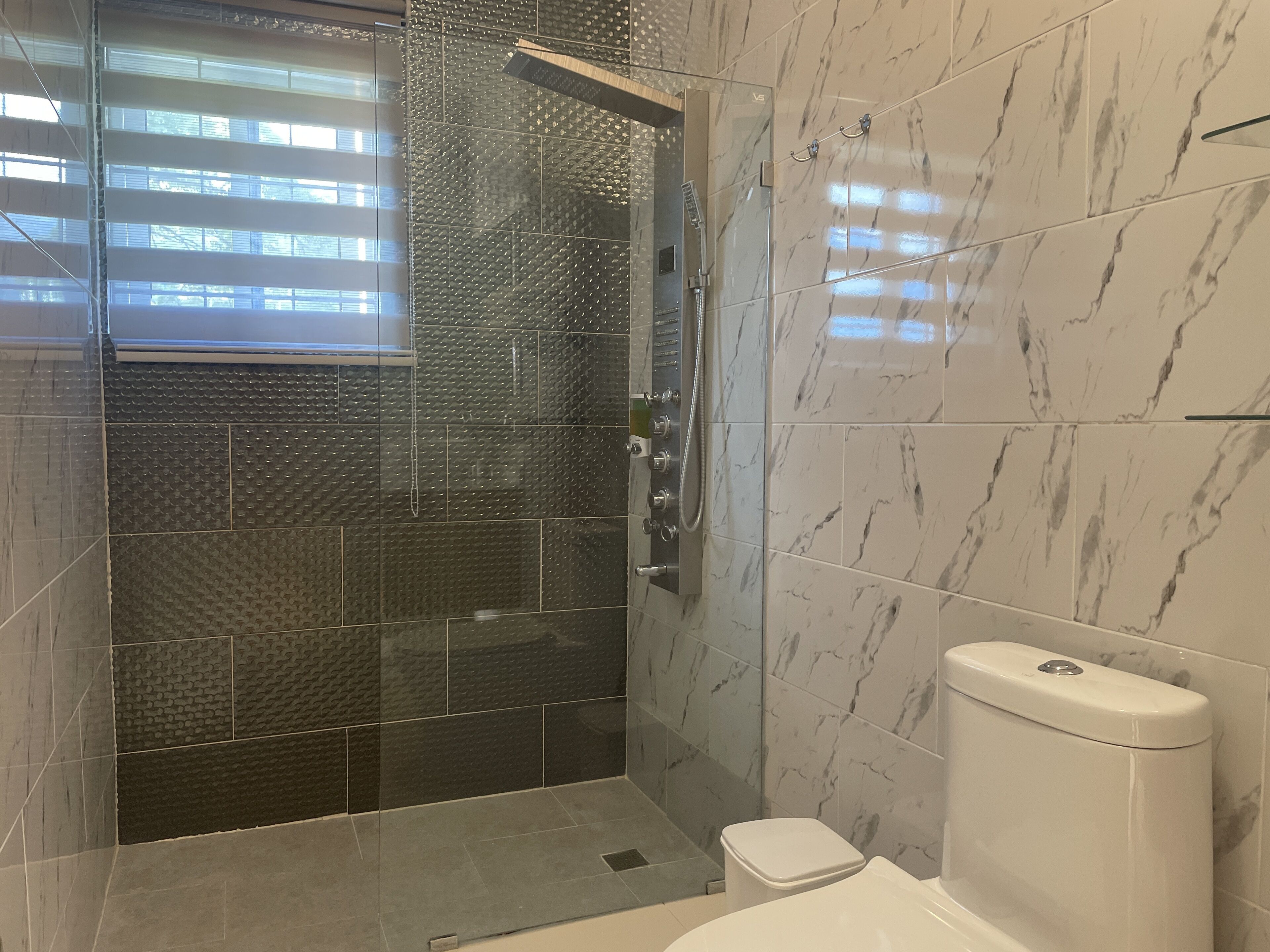 A modern bathroom with a glass-enclosed shower, a toilet, and a sink.