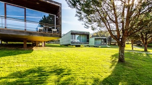 A modern building with large windows, a balcony with outdoor seating, and a well-maintained lawn. - Encosta do Paraíso – Apartamentos Turísticos (Guimarães)