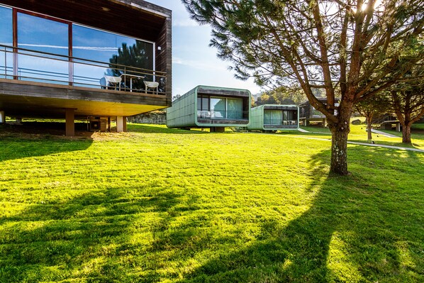 A modern building with large windows, a balcony with outdoor seating, and a well-maintained lawn. - Encosta do Paraiso - Apartamentos Turisticos (Guimarães)