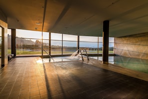 A large indoor pool with a view of a bridge and greenery. - Encosta do Paraiso - Apartamentos Turisticos (Guimarães)