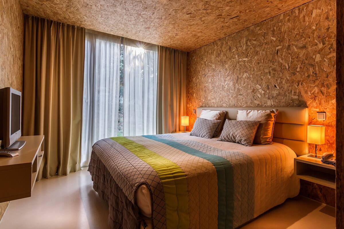 A hotel room with a large bed, a desk, a television, and a window with curtains.