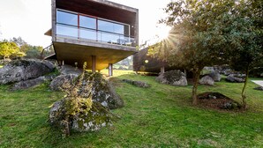 A modern house with a flat roof, large windows, and a balcony. - Encosta do Paraíso – Apartamentos Turísticos (Guimarães)