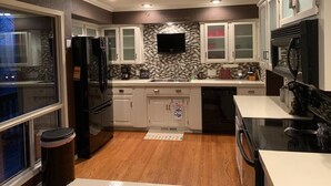 Una cocina moderna con armarios blancos, un refrigerador negro y un salpicadero de azulejos.