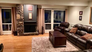 Una sala de estar acogedora con chimenea de piedra, sofá de cuero y una mesa de centro de madera.