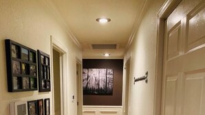Un pasillo con suelo de madera, paredes blancas y una puerta a la derecha.