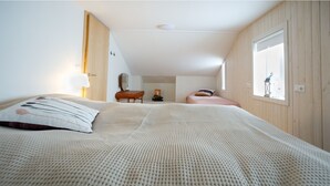 A bedroom with a large bed, a desk, a chair, and a window. - Original North Country House (Laugar)