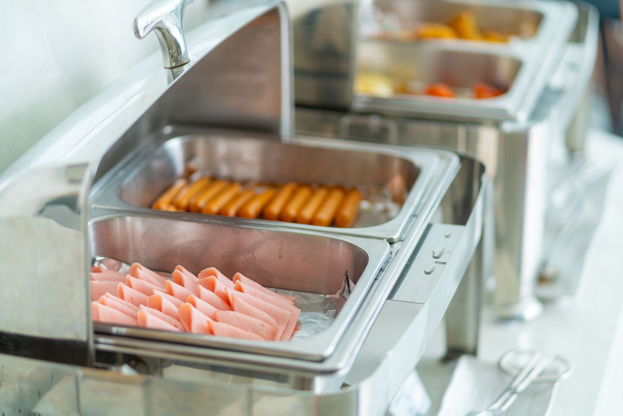 En buffet med forskellige madmuligheder, herunder pålæg og hotdogs.