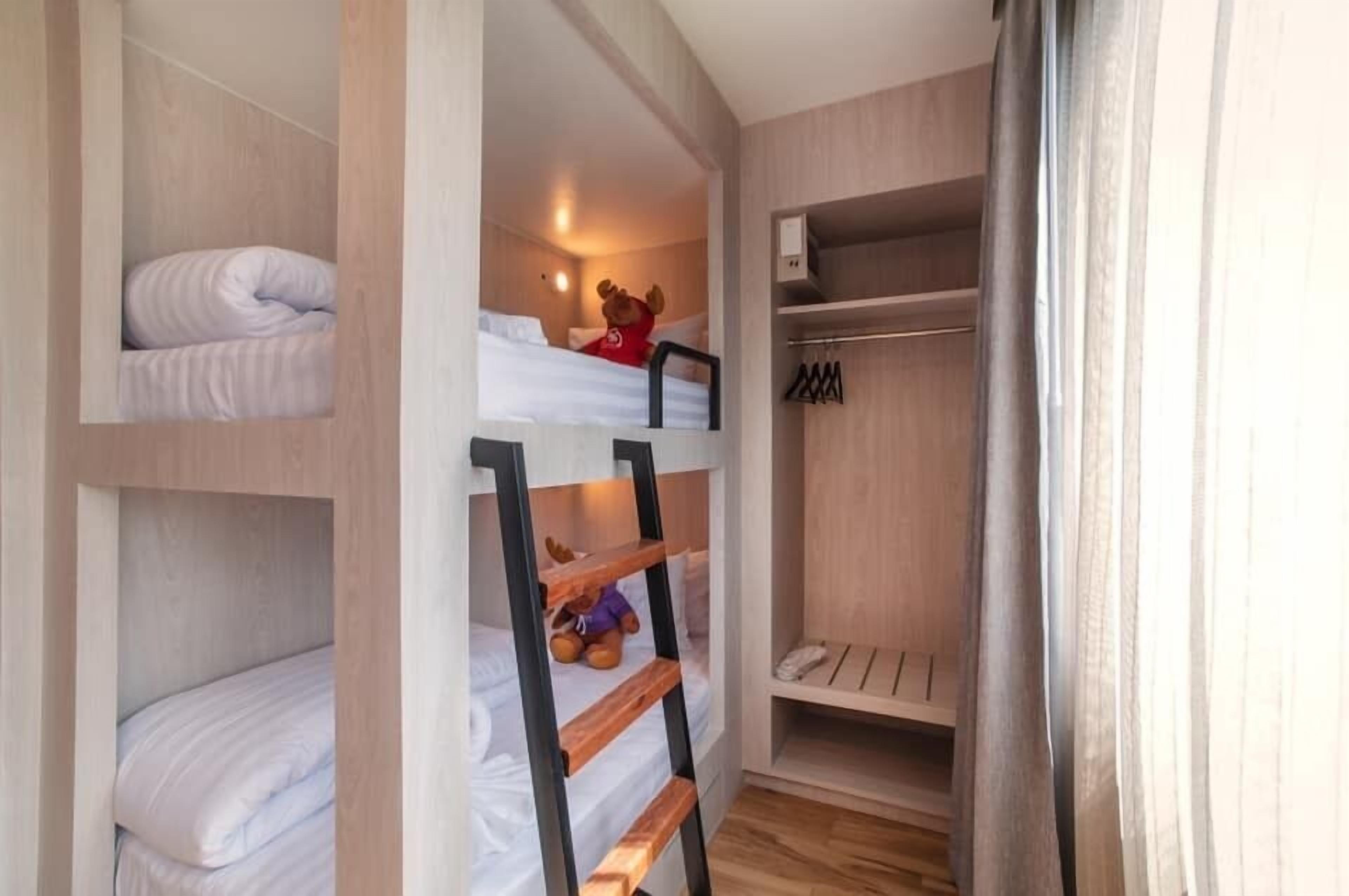A bunk bed room with a wardrobe and a shelf.
