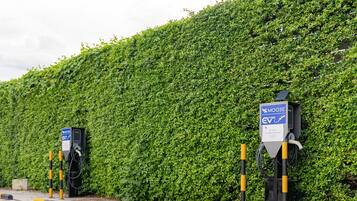 Uma área de estacionamento com estações de carregamento para veículos elétricos, sinalizada exclusivamente para veículos elétricos, e uma placa azul indicando uma estação Moose EV.