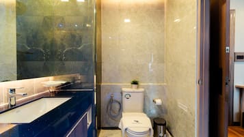 Une salle de bain moderne avec un lavabo en marbre, des toilettes et une douche.
